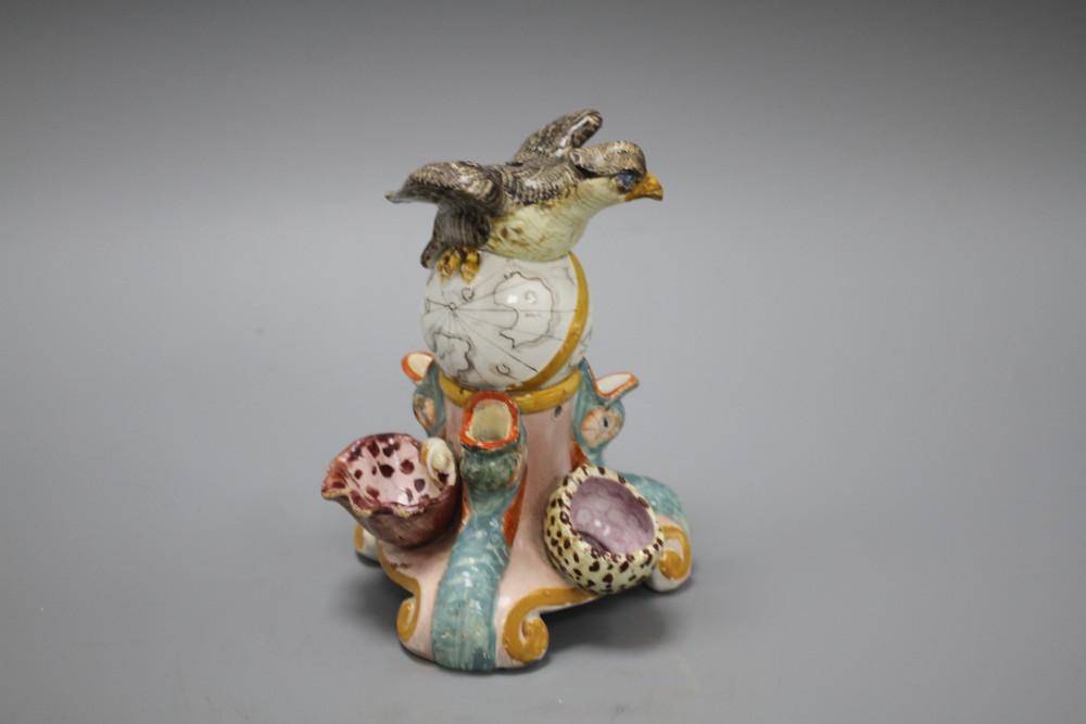 An early 19th century Staffordshire inkwell, modelled with an eagle perched upon a globe above three dolphins and shells, height 15cm